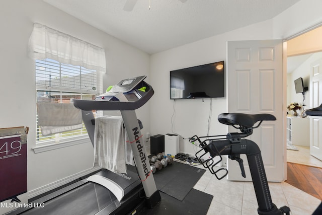 exercise room with a ceiling fan and tile patterned flooring