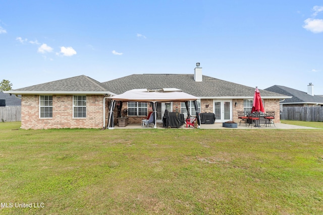 back of property featuring a lawn, brick siding, fence, and a patio