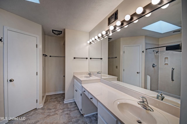 bathroom with vanity, a textured ceiling, a shower with shower door, and a skylight