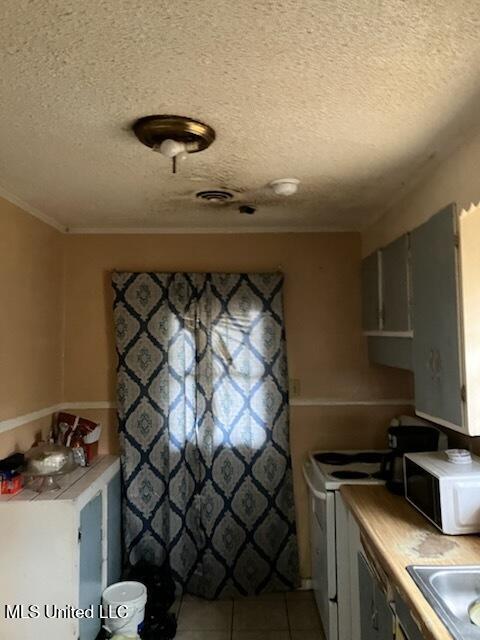 1710 Eastward Dr, Gulfport, MS 39501 - kitchen with white appliances, light tile patterned floors, a textured ceiling, a sink, and light countertops