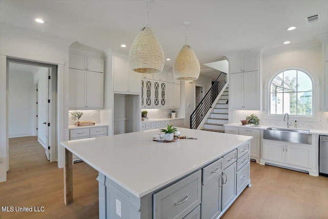 kitchen featuring white cabinetry, decorative backsplash, light wood-type flooring, and a kitchen island