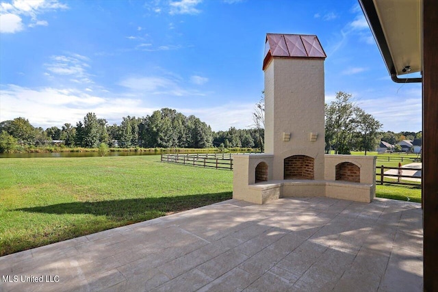 view of patio featuring an outdoor brick fireplace and a rural view