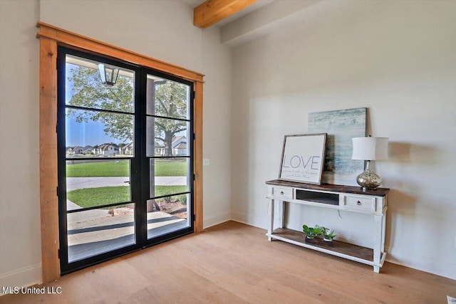 doorway with beamed ceiling and light hardwood / wood-style flooring