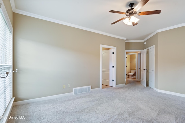 unfurnished bedroom with crown molding, carpet, baseboards, ensuite bath, and ceiling fan