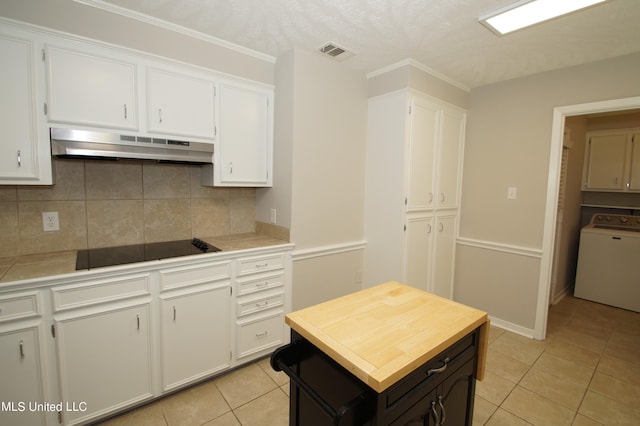 kitchen with black electric stovetop, decorative backsplash, washer / clothes dryer, exhaust hood, and white cabinetry