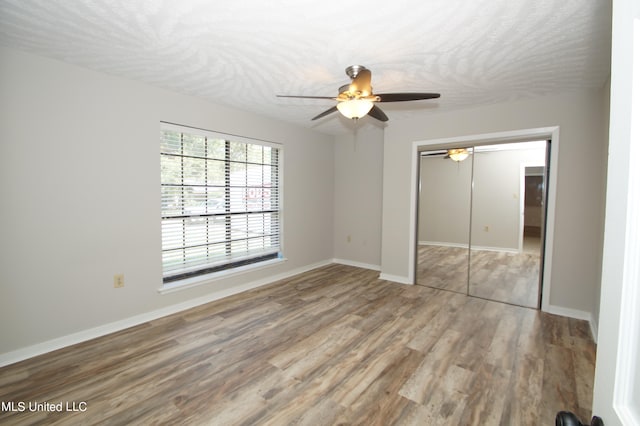 unfurnished bedroom with a closet, ceiling fan, hardwood / wood-style flooring, and a textured ceiling