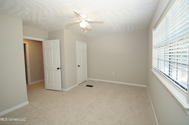 unfurnished bedroom with ceiling fan, a textured ceiling, and light colored carpet