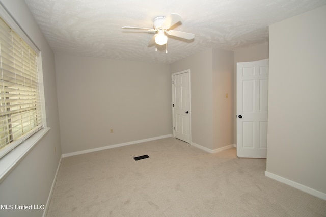 spare room with light carpet, a textured ceiling, and ceiling fan