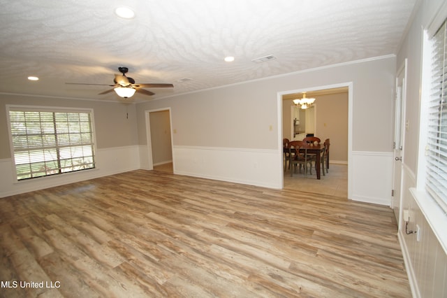 spare room featuring ornamental molding, light hardwood / wood-style flooring, a textured ceiling, and ceiling fan with notable chandelier