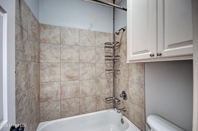 bathroom with toilet and tiled shower / bath