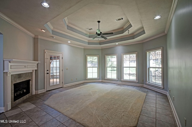 unfurnished living room with ornamental molding, a fireplace, a tray ceiling, and ceiling fan