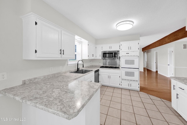 8279 Dunn Ln, Olive Branch, MS 38654 - kitchen featuring appliances with stainless steel finishes, a peninsula, light countertops, white cabinetry, and light tile patterned flooring