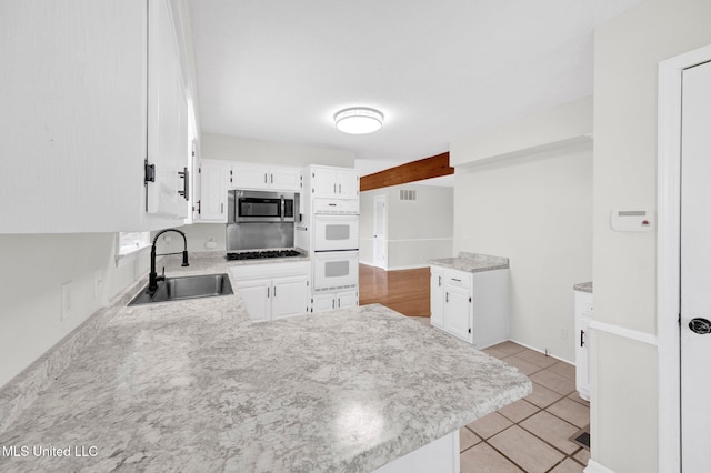 8279 Dunn Ln, Olive Branch, MS 38654 - kitchen with stainless steel microwave, a peninsula, white cabinets, light countertops, and double oven