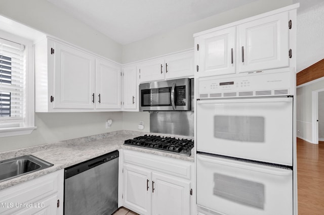 8279 Dunn Ln, Olive Branch, MS 38654 - kitchen with appliances with stainless steel finishes, white cabinetry, light countertops, and wood finished floors