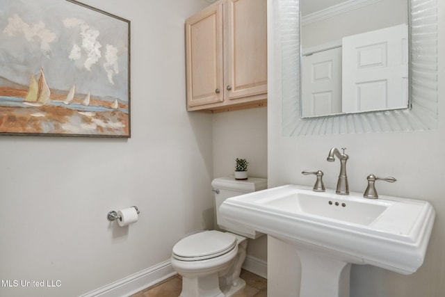 half bathroom with baseboards, a sink, toilet, and tile patterned floors