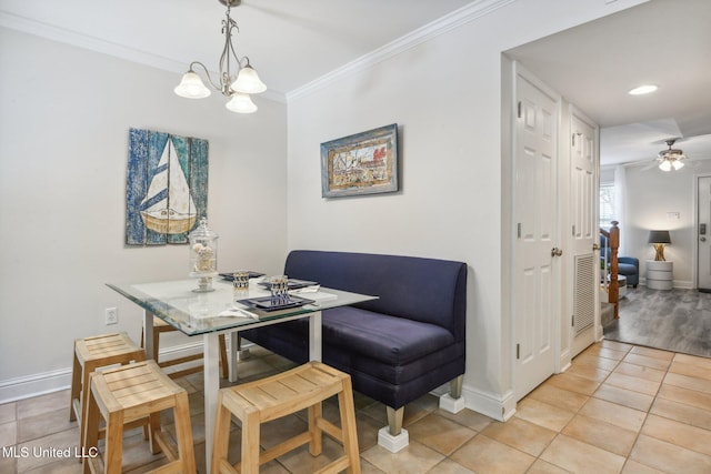 dining space with ceiling fan with notable chandelier, baseboards, crown molding, and light tile patterned flooring