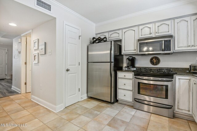 kitchen featuring light tile patterned flooring, stainless steel appliances, visible vents, baseboards, and crown molding