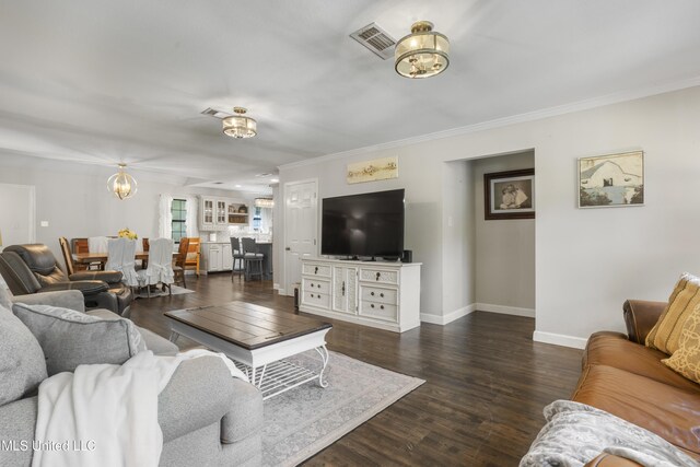living room with crown molding, an inviting chandelier, baseboards, dark wood-type flooring, and visible vents