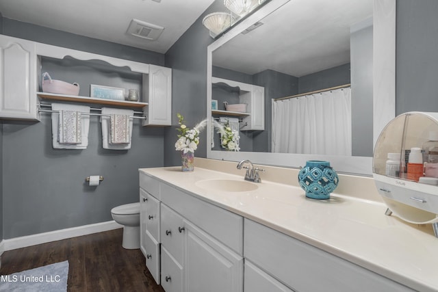 bathroom featuring vanity, toilet, baseboards, wood finished floors, and visible vents