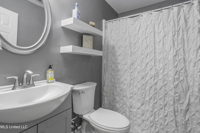 bathroom featuring toilet, curtained shower, and vanity
