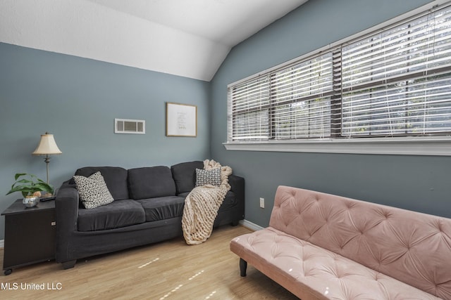 living area with visible vents, baseboards, lofted ceiling, and wood finished floors
