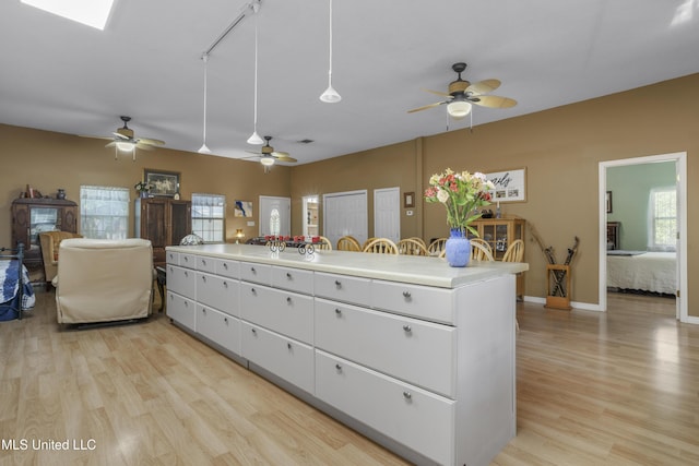 kitchen with light wood-type flooring, light countertops, ceiling fan, and white cabinets