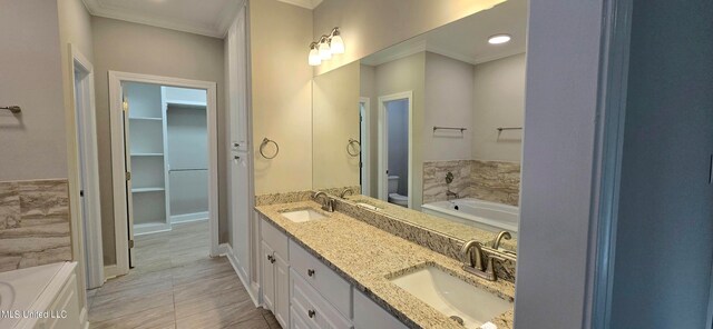 bathroom featuring vanity, ornamental molding, toilet, and a bathing tub