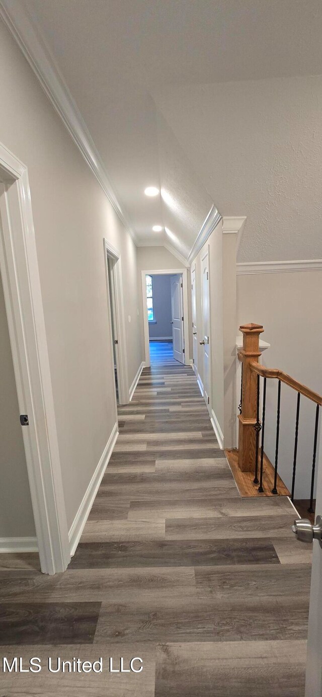 corridor featuring lofted ceiling, ornamental molding, and dark wood-type flooring