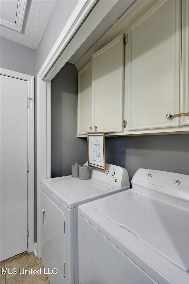 washroom featuring washer and dryer, a textured ceiling, and cabinets