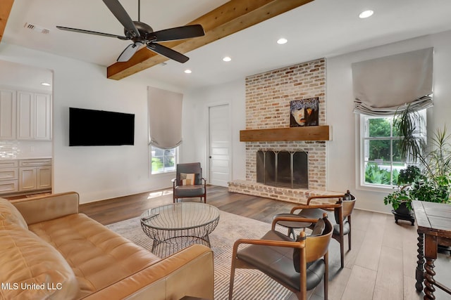 living room with beamed ceiling, plenty of natural light, and light wood-type flooring