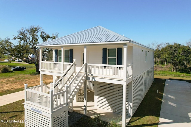 coastal inspired home with stairs, covered porch, and metal roof