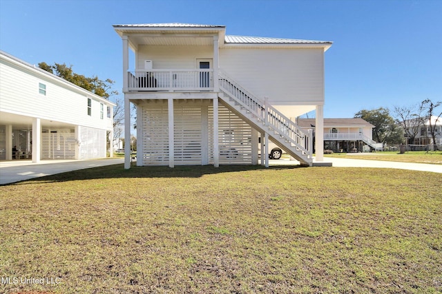 back of house with metal roof, a lawn, and stairway