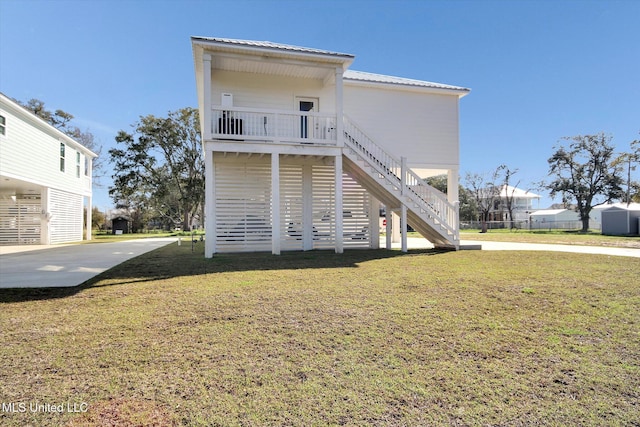 back of property with metal roof, a yard, and stairway