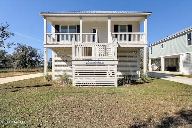 view of front of house featuring concrete driveway, stairs, a front yard, covered porch, and metal roof