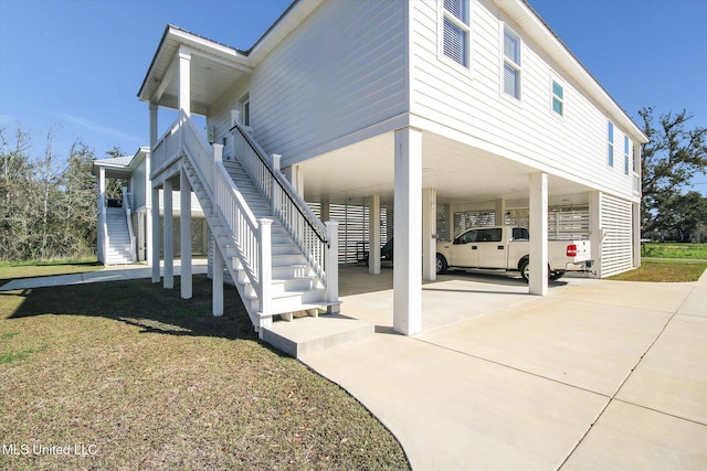 view of property exterior featuring stairs, a carport, concrete driveway, and a yard