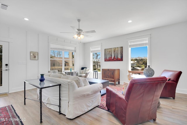 living area with light wood finished floors, plenty of natural light, and a ceiling fan