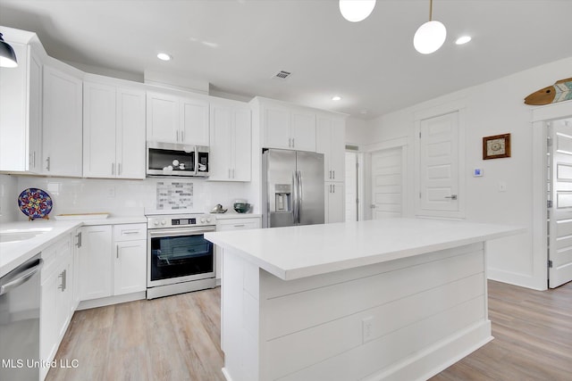 kitchen with stainless steel appliances, tasteful backsplash, visible vents, and light wood finished floors