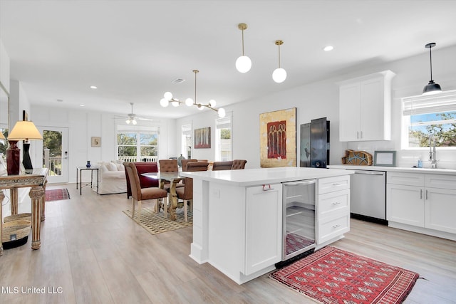 kitchen featuring wine cooler, stainless steel dishwasher, a healthy amount of sunlight, and light countertops