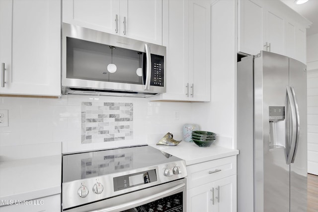 kitchen with backsplash, appliances with stainless steel finishes, white cabinets, and light countertops