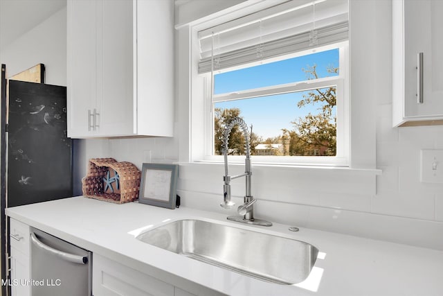 kitchen featuring a sink, backsplash, stainless steel dishwasher, white cabinets, and light countertops