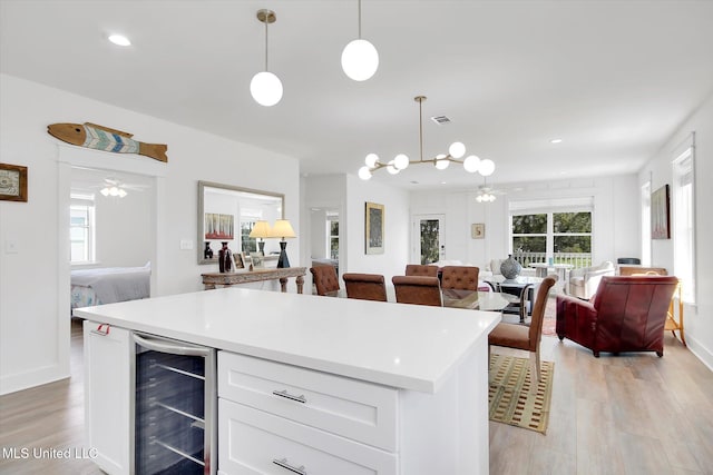 kitchen with visible vents, open floor plan, beverage cooler, and ceiling fan with notable chandelier