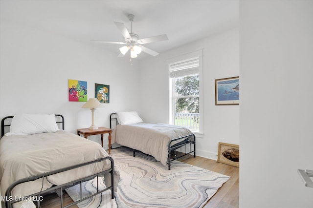 bedroom featuring a ceiling fan, baseboards, and light wood finished floors