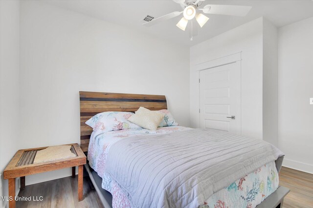 bedroom featuring visible vents, a ceiling fan, baseboards, and wood finished floors