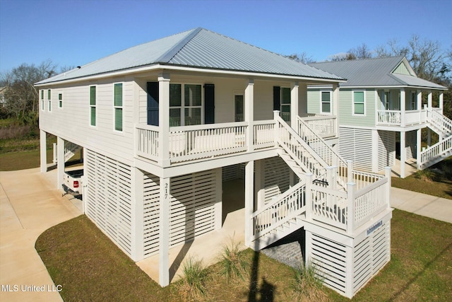 exterior space with metal roof, a porch, concrete driveway, and stairway