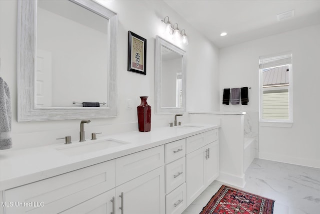 bathroom with double vanity, recessed lighting, marble finish floor, and a sink