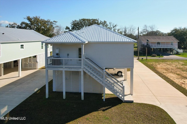 exterior space featuring stairway, a carport, concrete driveway, a lawn, and metal roof