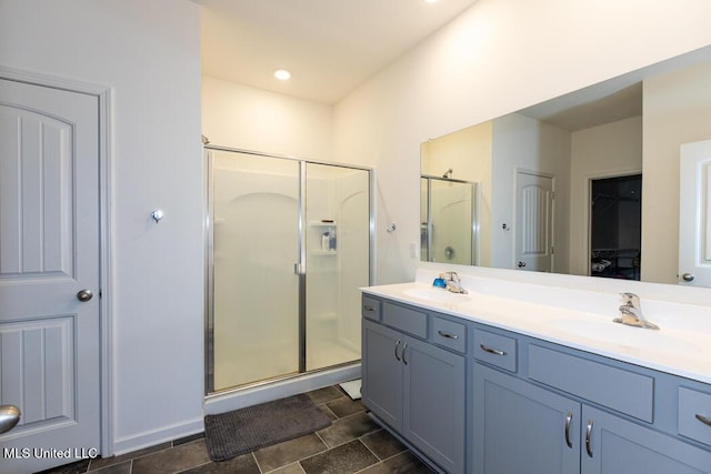 bathroom featuring a shower with shower door and vanity