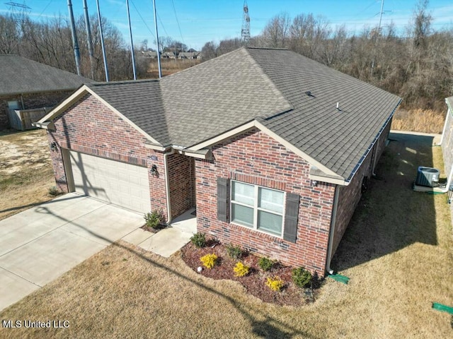 view of front of property featuring a front yard, a garage, and central AC unit