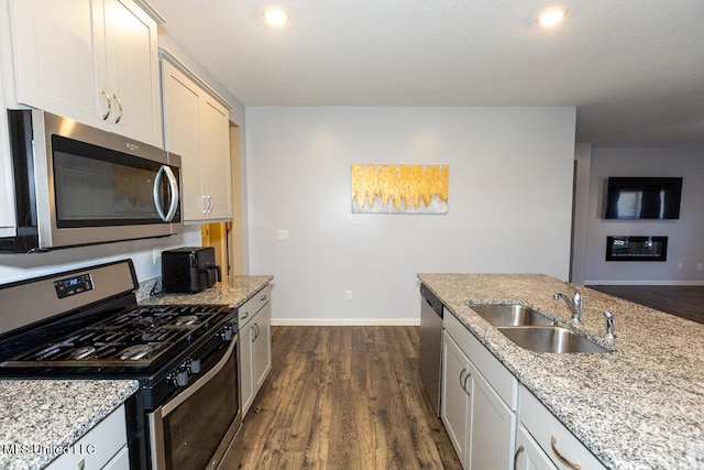 kitchen with sink, white cabinetry, appliances with stainless steel finishes, dark hardwood / wood-style flooring, and light stone counters