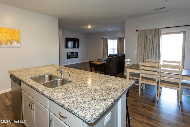 kitchen featuring a kitchen island with sink, dark wood-type flooring, stainless steel dishwasher, white cabinets, and sink